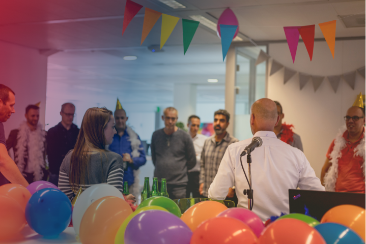 a group of employees in a room with a party atmosphere and balloons