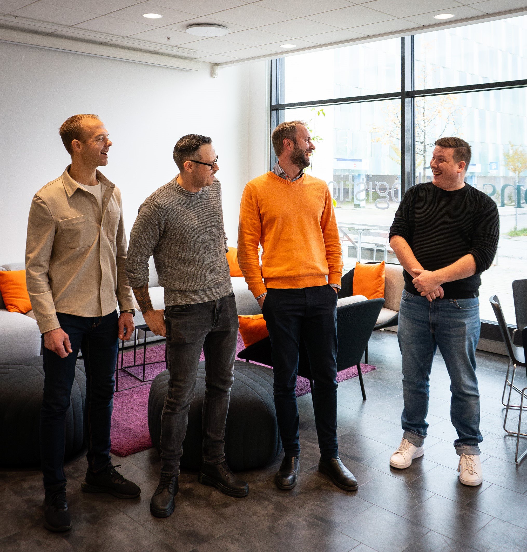 4 returning Consafe Logistics employees looking at each other and smiles