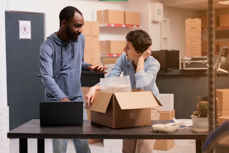 Two warehouse employees discussing packaging and inventory processes supported by Astro Go WMS.