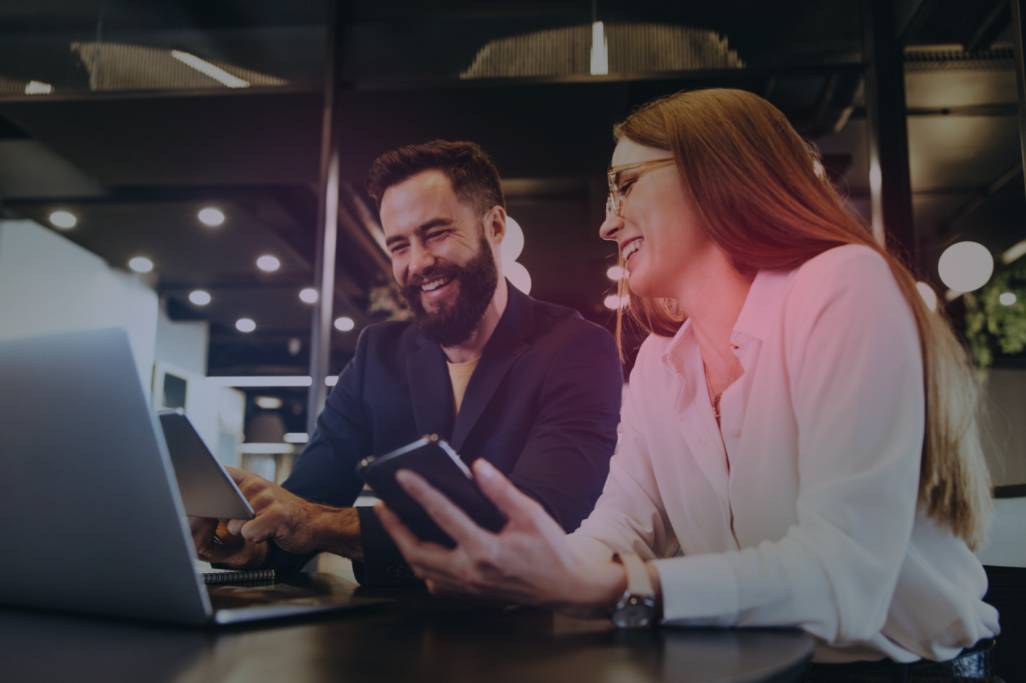 Two colleagues sit in front of a computer working together