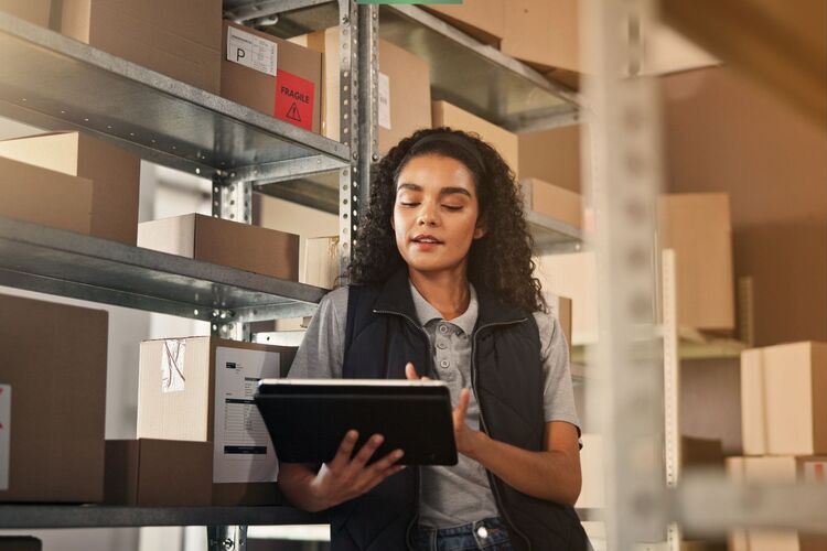 Warehouse worker using a tablet with Astro Go WMS to manage inventory on shelves with packages and fragile goods