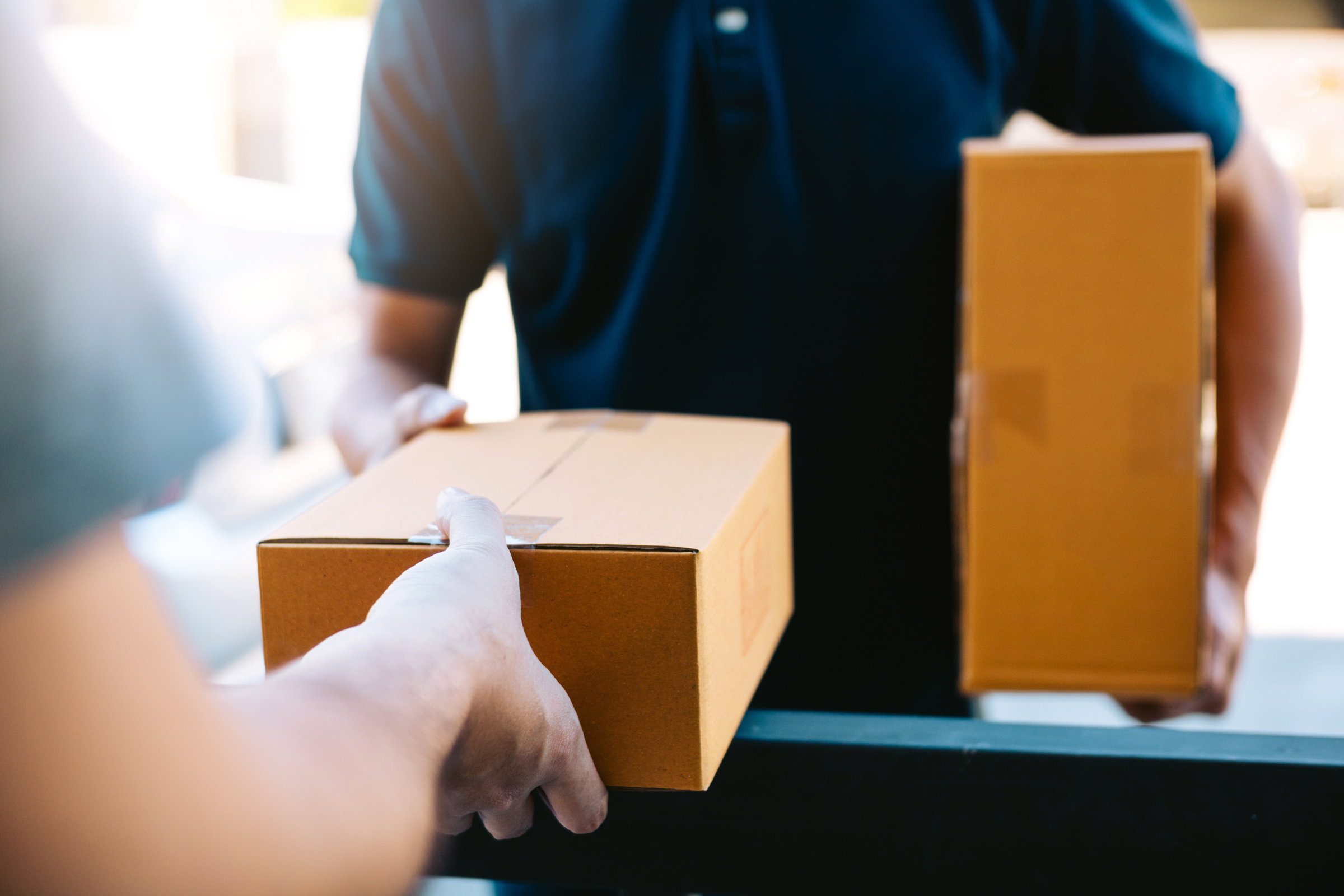 Close-up of hands of cargo staff delivering parcel ordered with black friday logistics to the recipient's hand.