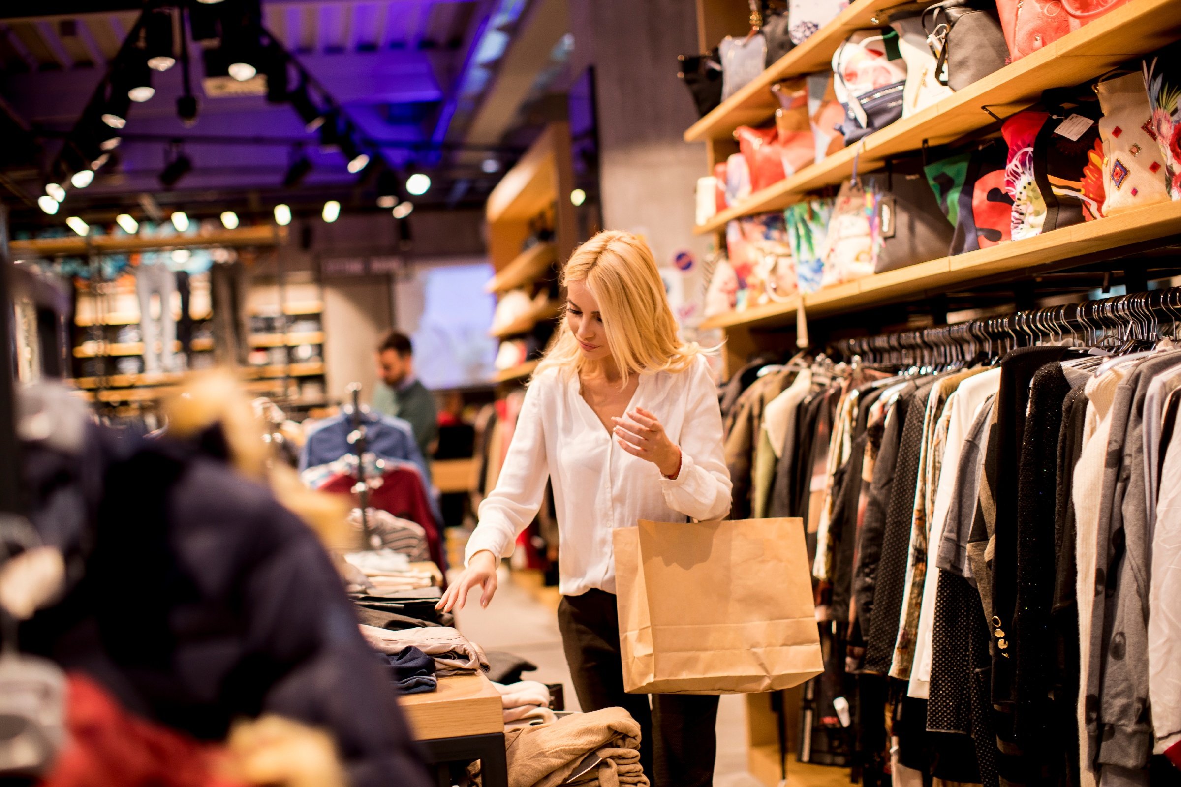 woman with a shopping bag looking a clothes in a gina tricot store